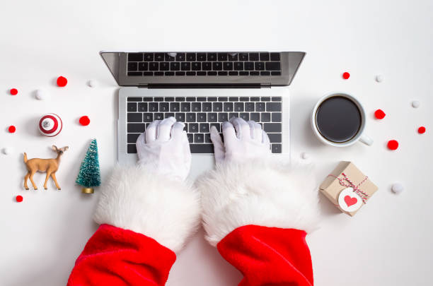 Santa typing on laptop with Christmas decorations