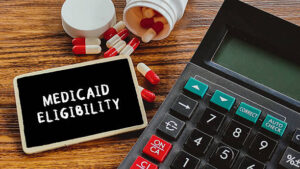 Medicaid eligibility sign next to calculator and prescription pills